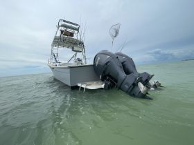 A fishing boat is captured from the back, showcasing its powerful twin engines and fishing gear, set against a serene water backdrop.