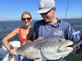 A joyful moment on the water as a couple proudly displays their impressive catch while fishing — a perfect highlight of a fun day on the boat.