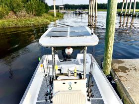 A view of the helm area of a fishing boat, showcasing the console and fishing gear, with a captain at the wheel ready for an adventure on the water.