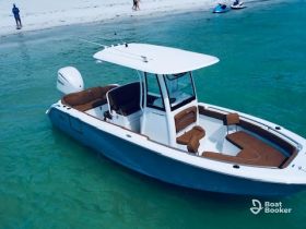 A sleek speedboat anchored in clear turquoise waters, with a sandy beach in the background, perfect for a day of fun on the water.