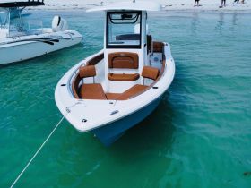 A sleek speedboat anchored in clear turquoise waters, showcasing its stylish design and comfortable seating — perfect for a day on the water.