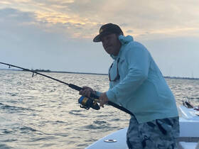 A fisherman reels in a catch while enjoying a day on the water, showcasing the thrill of fishing adventures.