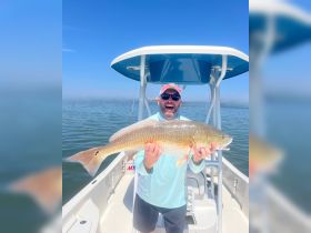 A joyful angler proudly displays his catch aboard a boat, showcasing the thrill of fishing on the water.