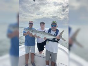 A group of anglers proudly displays their impressive catch while fishing on a boat — a perfect moment of celebration on the water.