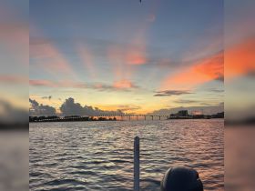 A stunning sunset view from a boat, showcasing vibrant colors in the sky and a bridge in the distance — perfect for evening cruises and scenic photography.
