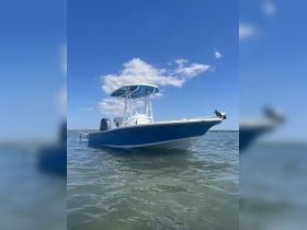 A sleek speedboat glides through clear waters under a bright blue sky, showcasing its stylish design and perfect for thrilling water adventures.