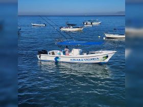 A speedboat named 'Anara Valeria' is anchored in calm waters, showcasing its fishing gear and vibrant design — ideal for fishing trips in Puerto Vallarta.