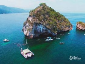 A stunning aerial view of a catamaran near a picturesque island, with guests enjoying snorkeling in the vibrant waters — a perfect destination for adventure seekers.