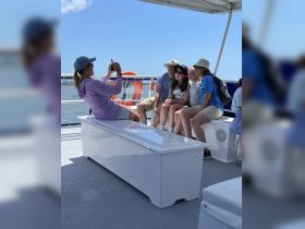 A family enjoys a fun moment on a boat, capturing memories with a group photo under the sun — perfect for family outings and celebrations on the water.