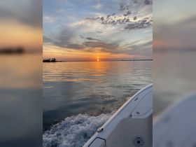 A serene sunset view from the side of a boat, showcasing the tranquil waters and vibrant colors of the sky — perfect for evening cruises.