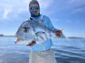 A proud angler holds up a large fish while out on the water, showcasing a successful fishing trip.