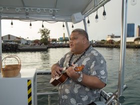 A musician performs on a boat, creating a lively atmosphere with music and entertainment — perfect for enhancing the boating experience.