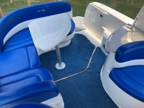 Interior view of a Sea Ray boat featuring comfortable blue seating and a table, ideal for relaxing on the water.