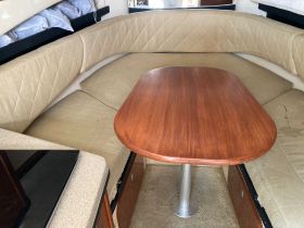 Cozy interior seating area of a boat featuring a round table and plush cushions, perfect for dining or relaxing while on the water.