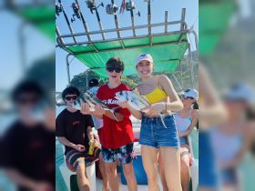 A group of friends celebrates their successful fishing trip, proudly displaying their catch aboard a boat — a perfect day on the water filled with fun and adventure.