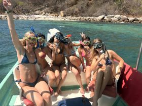 A lively group of friends enjoys a snorkeling adventure on a boat, showcasing excitement and camaraderie in a beautiful aquatic setting.