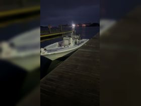 A speedboat docked at night, illuminated by nearby lights, showcasing its sleek design against the tranquil waters.