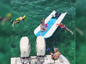 A joyful family enjoys a day of fun in the sun, with kids playing on a paddleboard and swimming in crystal-clear waters — perfect for summer adventures.