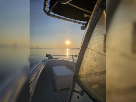 A serene view from the front of a boat at sunset, showcasing the calm waters and beautiful reflections — perfect for peaceful evening cruises.