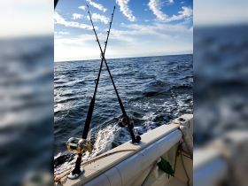 Fishing rods and reels are set up on the boat, ready for an exciting day of deep-sea fishing in open waters.