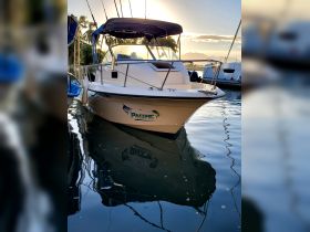 A stunning view of a fishing boat named 'Pacific' docked in calm waters, reflecting the serene surroundings and perfect for fishing adventures.