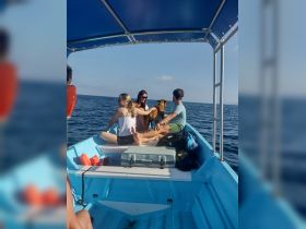 A cheerful group enjoys a day on the water with their dog, creating memorable moments aboard a small boat in the ocean.