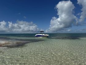 A speedboat anchored in clear, shallow waters under a bright blue sky, perfect for a day of relaxation and exploration on the water.