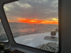 A stunning sunset view from the deck of a boat, showcasing vibrant colors reflecting on the water — perfect for capturing the serene beauty of evening cruises.