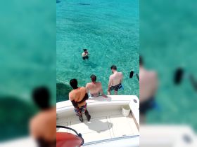 A group of friends enjoys a day in the clear waters, with one person snorkeling while others watch from the boat — a perfect moment of fun and adventure on the water.