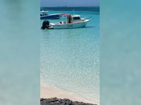 A picturesque view of a boat named 'Cool Runnings' anchored in crystal-clear waters, showcasing the serene beauty of a tropical destination.