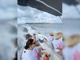 A lively group enjoys a boat ride, sipping drinks and soaking up the sun — perfect for a fun day on the water.