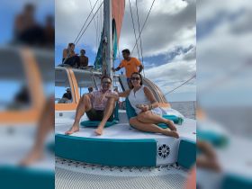 A couple enjoys a relaxing moment aboard a catamaran with friends, capturing the essence of a fun sailing adventure on the open water.