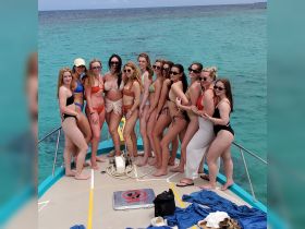 A lively group of friends poses together on the deck of a boat, enjoying a fun day on the water — perfect for celebrations and memorable outings.