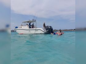 A lively group enjoys a day on the water, swimming near a fishing boat in clear turquoise waters — perfect for family adventures and aquatic fun.