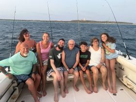 A joyful family poses together on a fishing boat, capturing a memorable moment on the water — perfect for family fishing adventures.