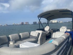 A cozy interior view of a pontoon boat featuring comfortable seating and a helm, perfect for relaxing on the water while enjoying scenic views of the skyline.