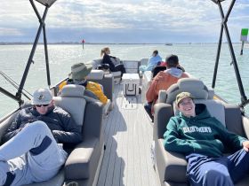 A group of friends relaxes on a pontoon boat, enjoying a sunny day on the water — perfect for social outings and leisure activities.