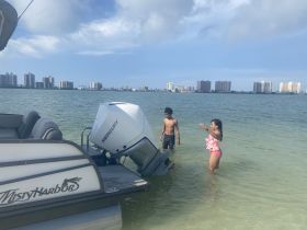 Two children enjoy a fun day swimming near a Misty Harbor pontoon boat, showcasing a perfect family outing on the water.