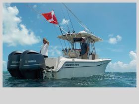 Two men aboard a Grady-White boat equipped for fishing, enjoying a day on the ocean with vibrant blue skies and clear waters.