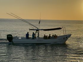A group of friends enjoys a fishing trip on a boat during a stunning sunset, creating the perfect backdrop for memorable on-water experiences.