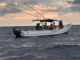 A group of friends enjoys a fishing trip on the ocean aboard the boat 'ROMA' during a beautiful sunset, capturing the essence of adventure and camaraderie.