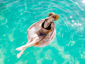 A woman enjoys a sunny day floating on a colorful inflatable in crystal-clear waters, perfect for relaxation and summer fun.