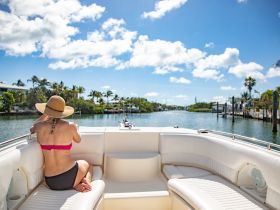 A woman relaxes on the deck of a boat, enjoying the sunny weather and scenic waterway views — an ideal moment for leisure and tranquility on the water.
