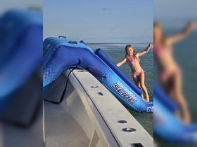 A young girl enjoys a colorful inflatable water slide on a boat, perfect for summer fun and water activities.