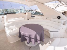 A stylish interior view of a boat's cabin featuring comfortable seating and a table, perfect for relaxation and dining while on the water.