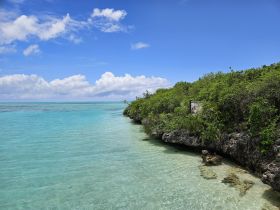 A stunning view of a tranquil coastline with crystal-clear turquoise waters and lush greenery, perfect for showcasing the beauty of island destinations.