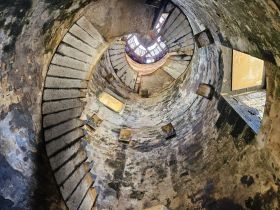 An abstract view of a spiral staircase within a structure, showcasing aged materials and textures. The image captures a unique perspective but lacks clarity.