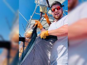 A joyful angler proudly displays a large catch aboard a fishing boat, capturing the excitement of a successful day on the water.