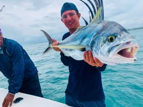 Two fishermen proudly display a large catch on a boat, showcasing the thrill of deep-sea fishing in the ocean.
