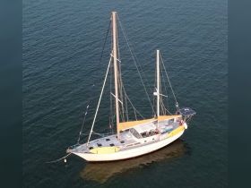 Aerial view of a beautifully crafted sailboat anchored in calm waters, showcasing its elegant design and vibrant colors.